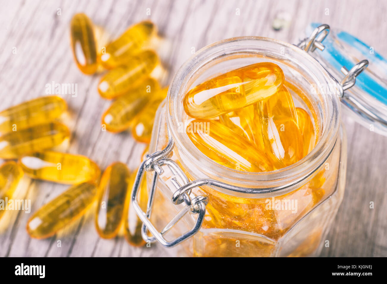 Close up of omega-3 fish fat oil capsules on wooden board in a jar Stock Photo