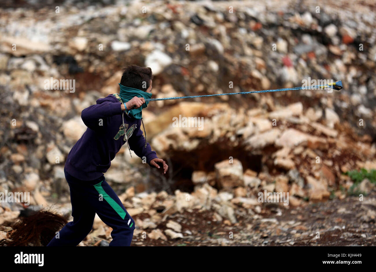 Nablus, West Bank, Palestinian Territory. 24th Nov, 2017. A Palestinian protester uses a slingshot to hurl stones towards Israeli security forces during clashes following a weekly demonstration against the expropriation of Palestinian land by Israel in the village of Kfar Qaddum, near Nablus in the occupied West Bank, on November 24, 2017 Credit: Shadi Jarar'Ah/APA Images/ZUMA Wire/Alamy Live News Stock Photo
