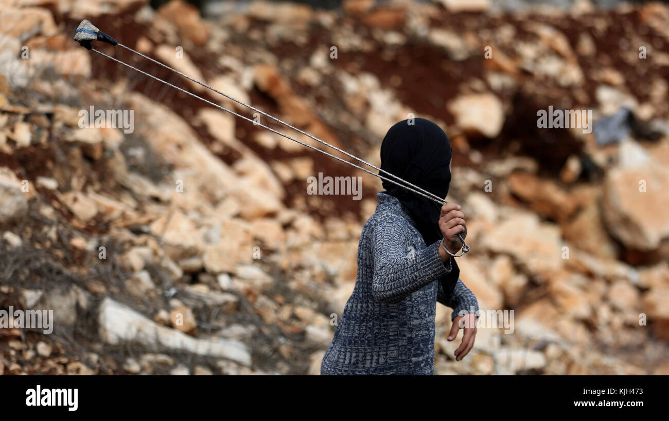 Nablus, West Bank, Palestinian Territory. 24th Nov, 2017. A Palestinian protester uses a slingshot to hurl stones towards Israeli security forces during clashes following a weekly demonstration against the expropriation of Palestinian land by Israel in the village of Kfar Qaddum, near Nablus in the occupied West Bank, on November 24, 2017 Credit: Shadi Jarar'Ah/APA Images/ZUMA Wire/Alamy Live News Stock Photo