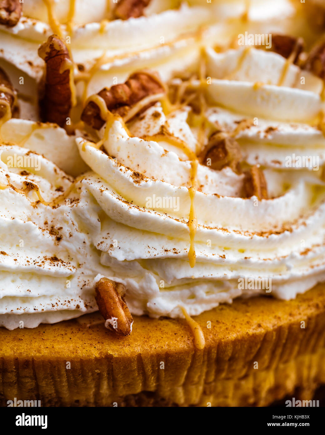 Enjoy Thanksgiving with a pumpkin pie cheesecake. Cheesecake is covered with whipped cream and pecans, then drizzled with caramel syrup. Stock Photo