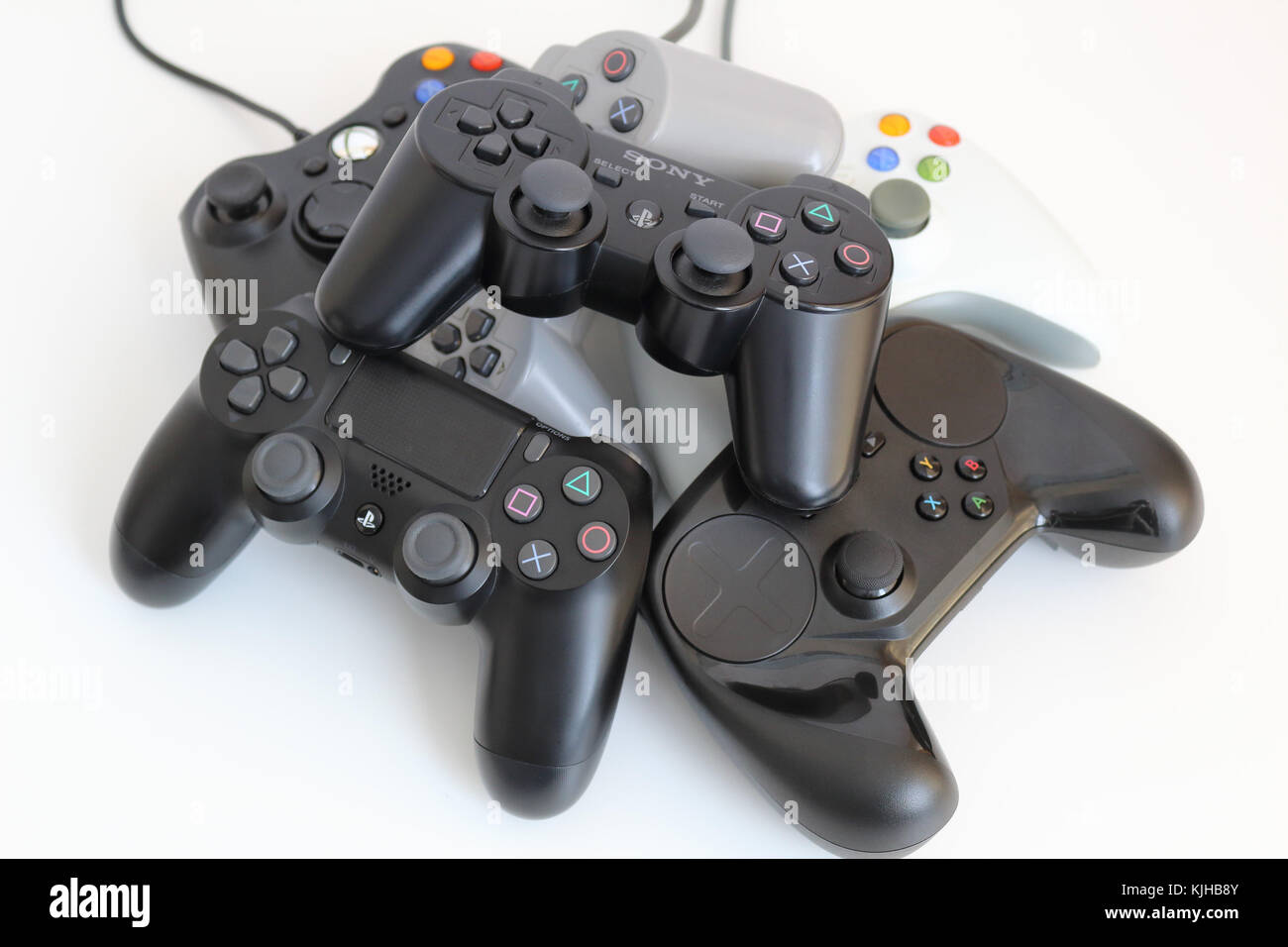 Various computer game controllers, arranged in a pile on a white background. Stock Photo