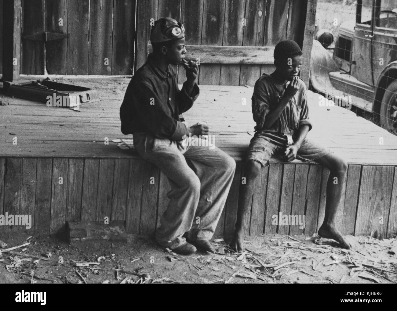 Black and white photograph of two homeless African-American boys, sitting, by Ben Shahn, Lithuanian born, American artist known for his work for the Farm Security Administration documenting the effects of the Great Depression, Natchez, Mississippi, 1935. From the New York Public Library. Stock Photo