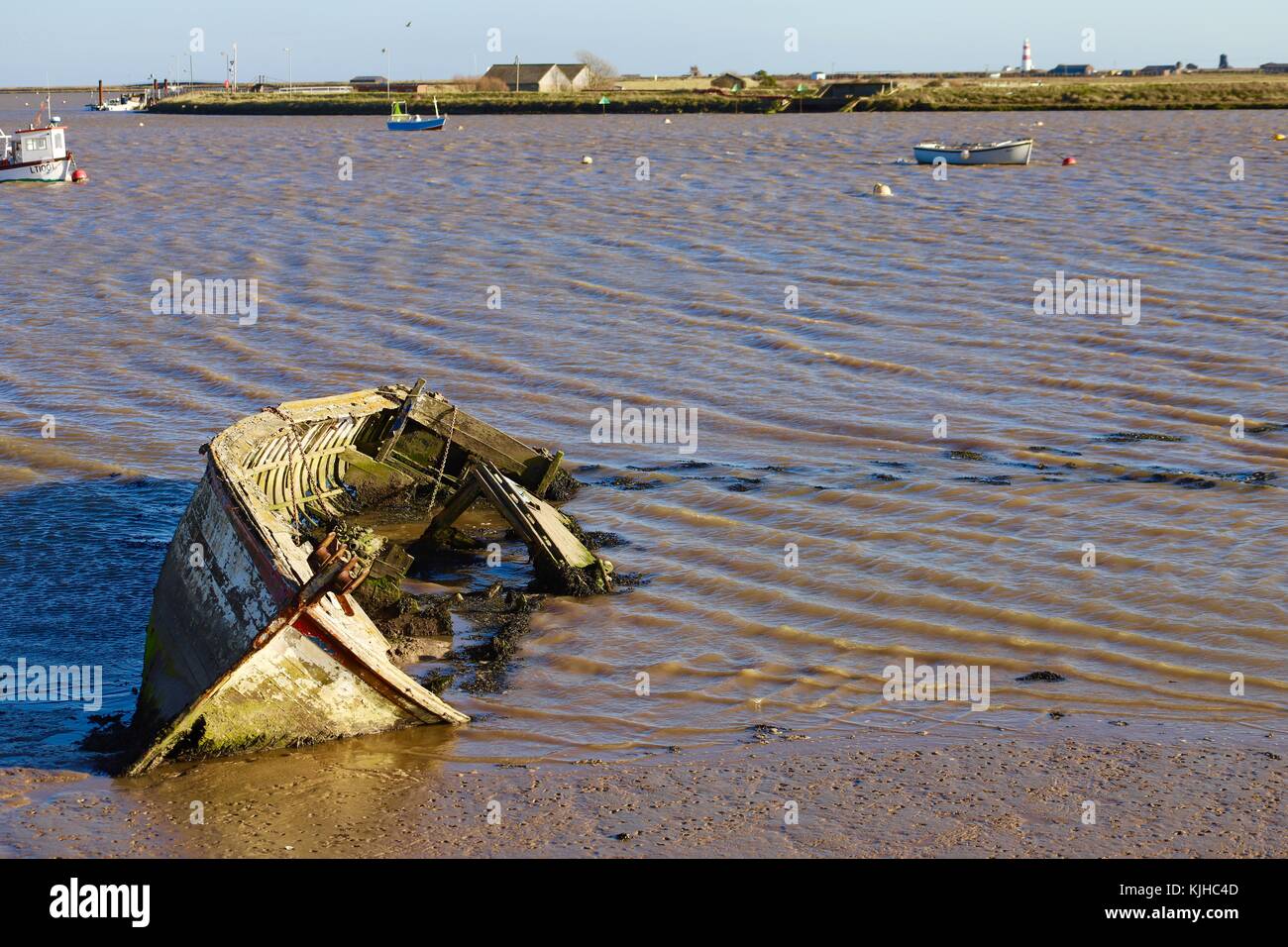 A derelict abandoned wooden boat on its side in the muddy River Alde at Orford Quay. Suffolk, UK. Stock Photo