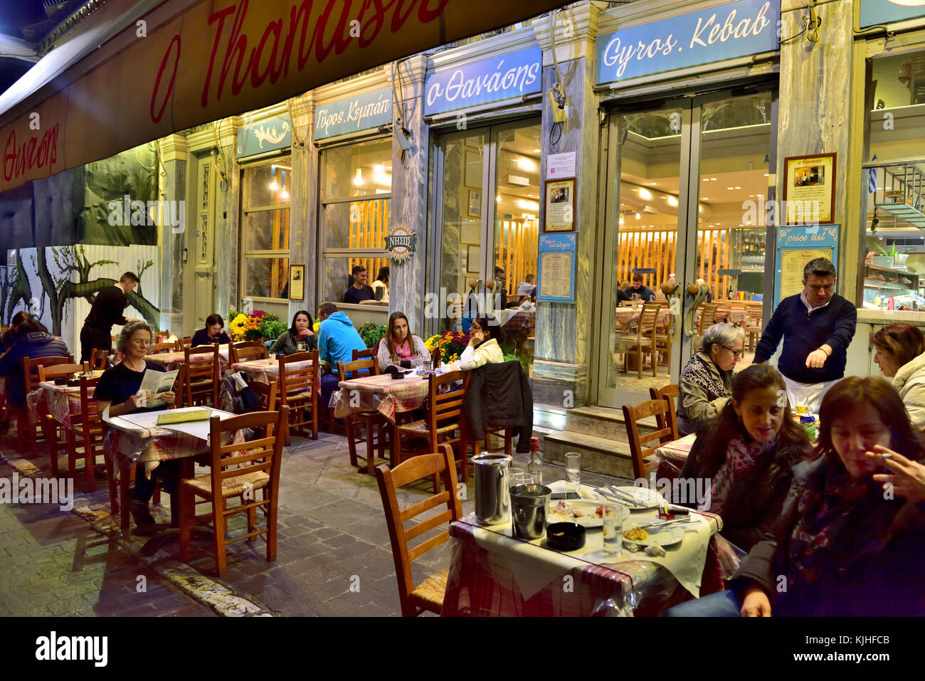 Evening sitting outside at Greek restaurant in popular picturesque Plaka district of central Athens near Monastiraki and Ermou street, Athens, Greece Stock Photo