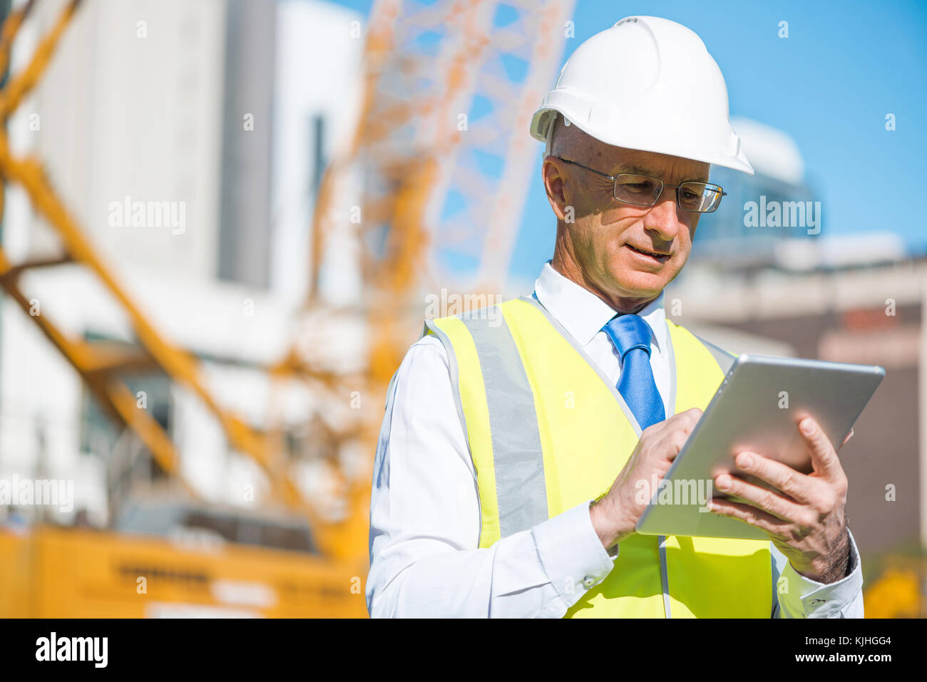Construction manager controlling building site and tablet device in his ...