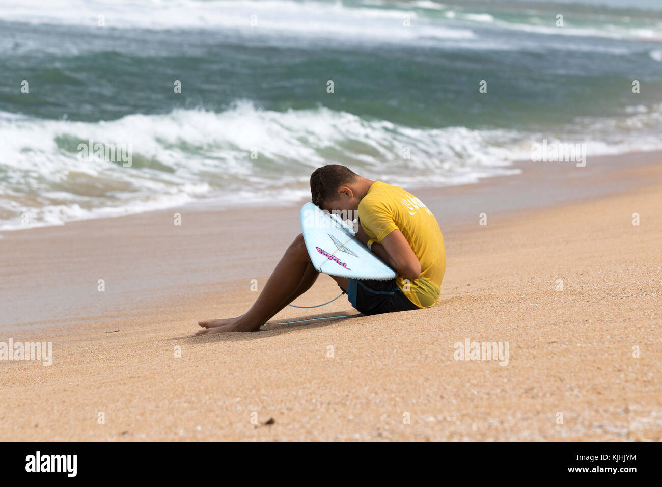 SAN JUAN, Puerto Rico — A local teen takes a quiet moment prior to his heat in the La Comprita charitable surf competition in Aviones, Puerto Rico, Nov. 11, 2017. The competition is hosted by Agua Salá Ministries, founded by Yossua Lugo over six years ago. Agua Salá is a religious outreach program focusing on helping improve Puerto Rican communities through donations and charitable works. Members of the ministry teach regular surf lessons to children, and host the monthly competition. Proceeds from the competition’s entrance fees and merchandise sales go directly to food and clothing donations Stock Photo