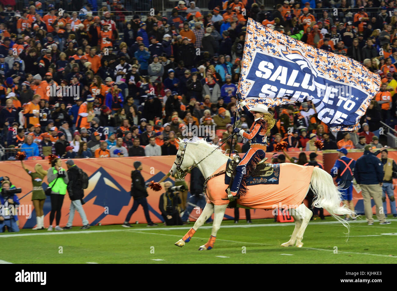 Thunder, Denver Bronco’s live mascot, runs onto the field during halftime while Ann Judge, Thunder’s trainer, holds a Salute to Service flag Nov. 12, 2017, at Sports Authority Stadium at Mile High in Denver. The Broncos, showing their respect, dedicated this game to honor all those who have served in the past and who currently serve in the U.S. military. (U.S. Air Force photo by Airman 1st Class Holden S. Faul/ Released) Stock Photo