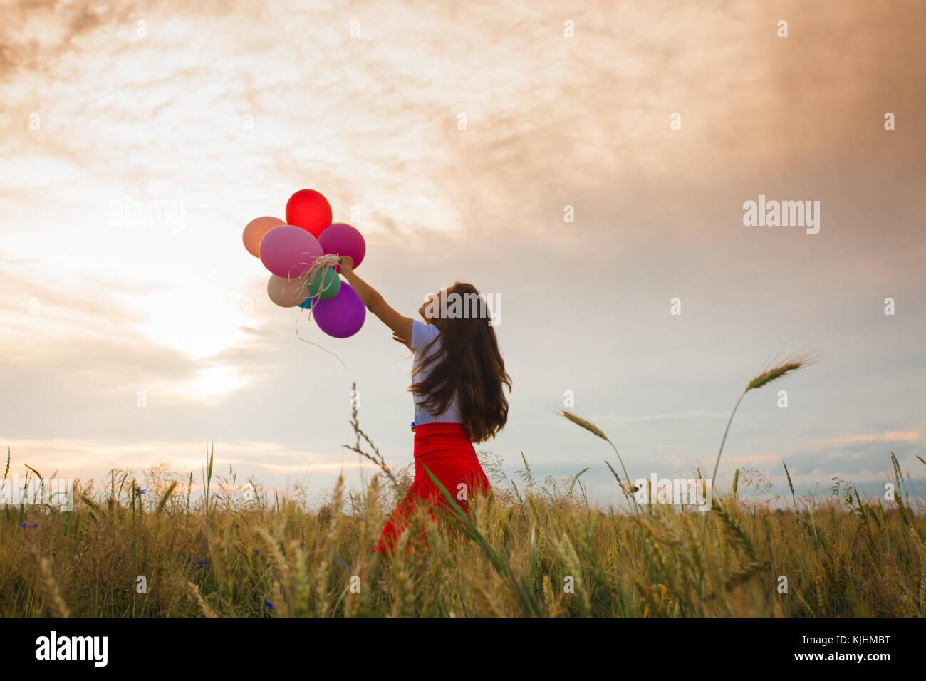 Girl with balloons in wheat field Stock Photo - Alamy