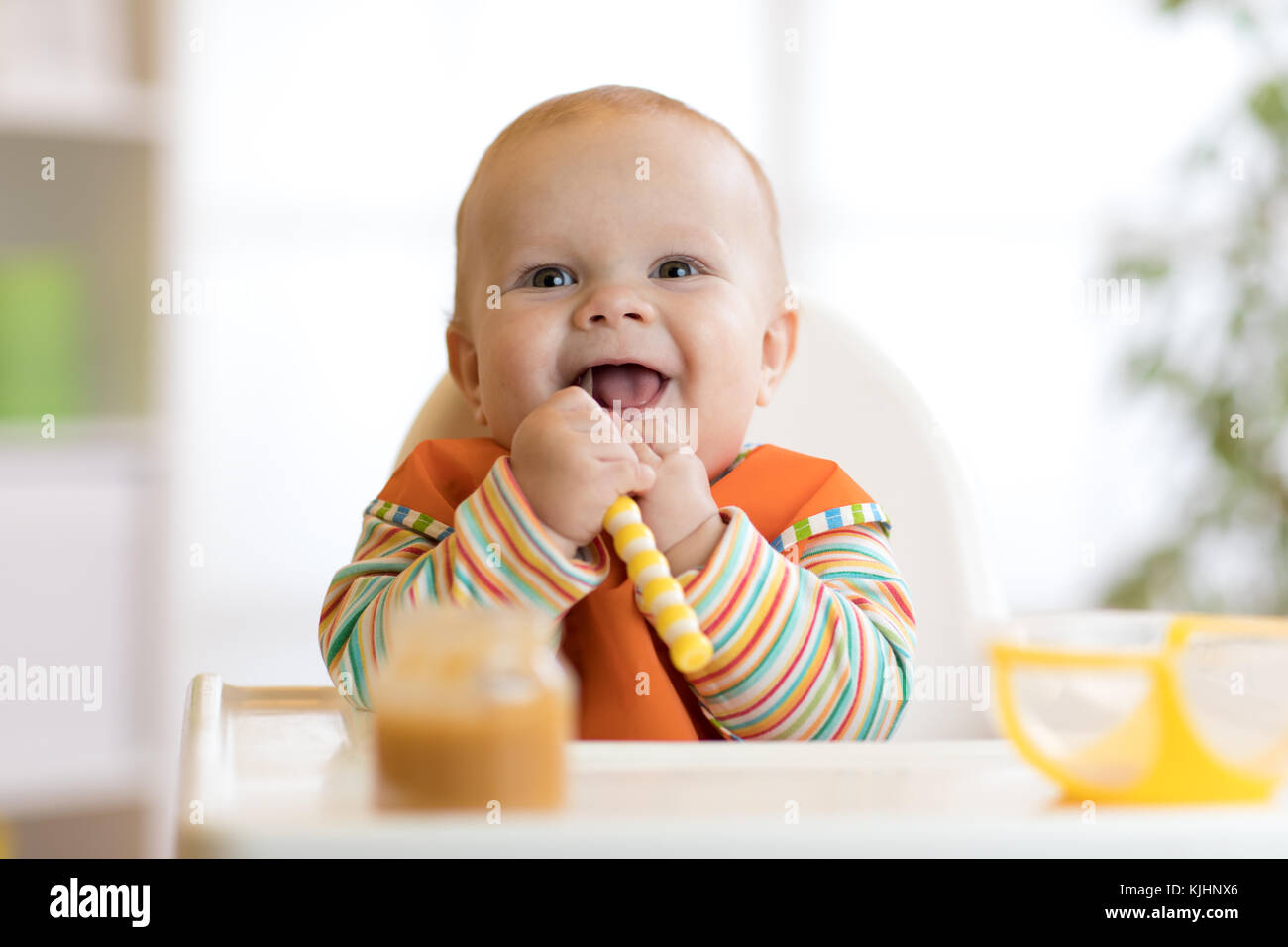 Happy infant baby boy spoon eats itself Stock Photo