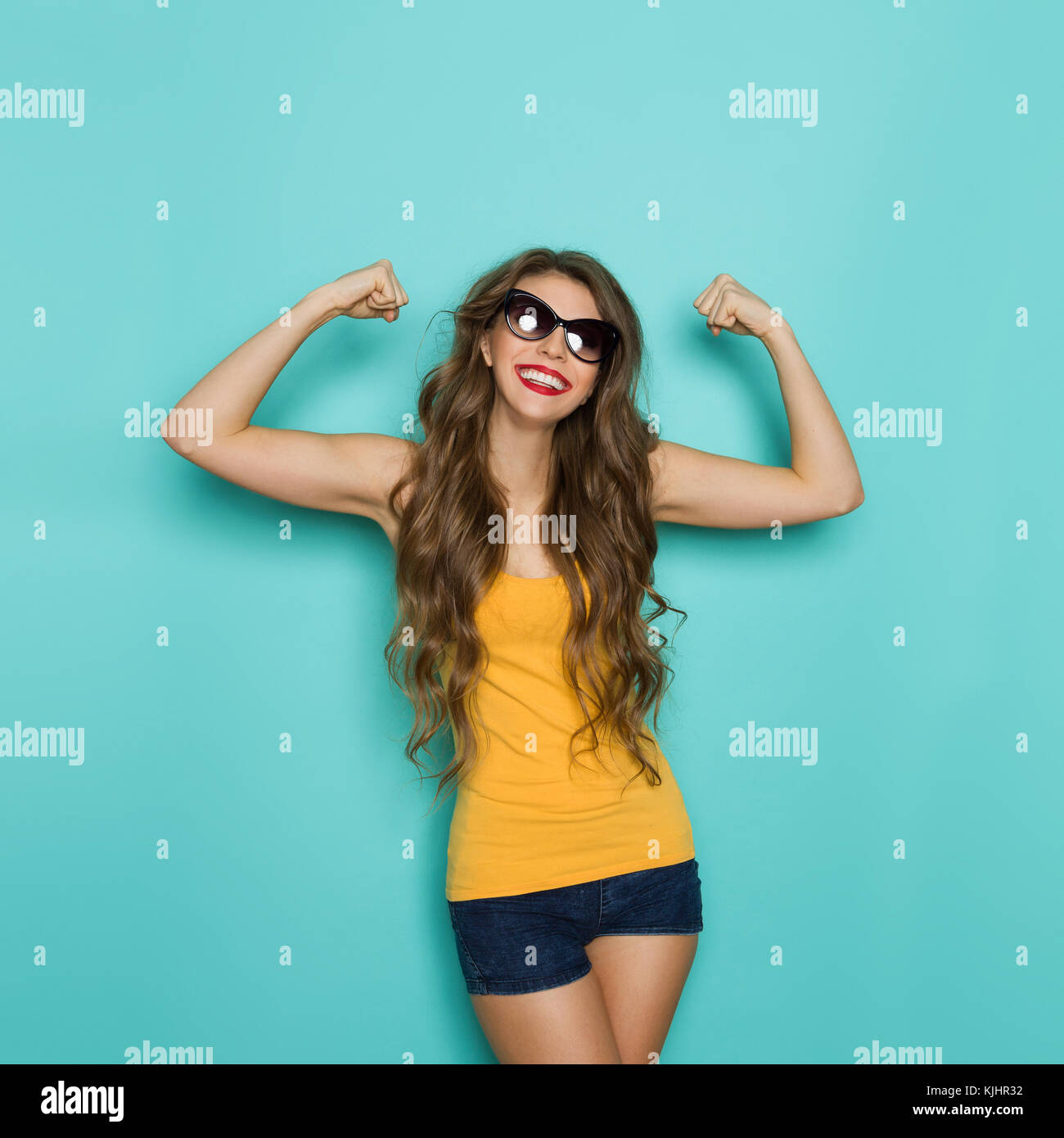 Beautiful young woman in sunglasses, jeans shorts and yellow shirt