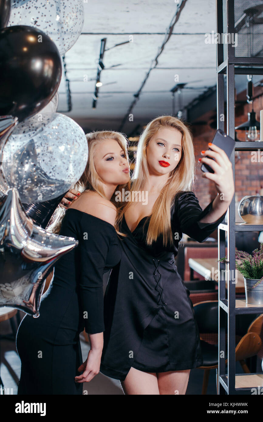 Two young women taking selfies in a cafe Stock Photo