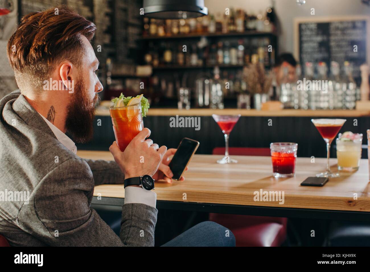 Man sitting in a bar looking at his phone Stock Photo
