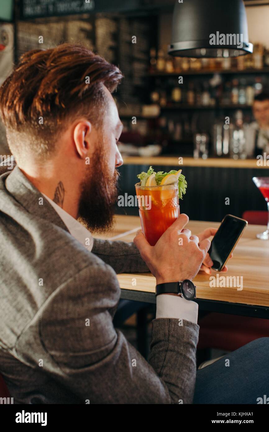 Man sitting in a bar looking at his mobile phone Stock Photo