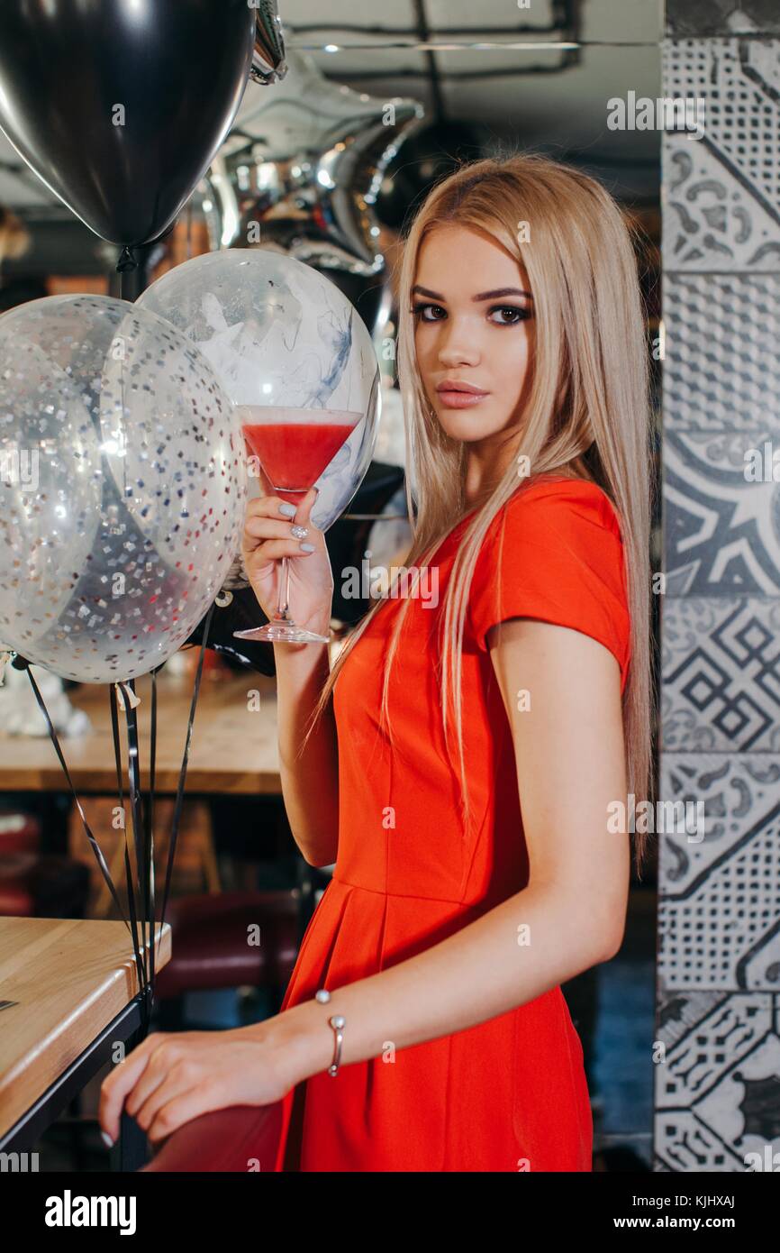 Woman standing in a bar holding a cocktail Stock Photo