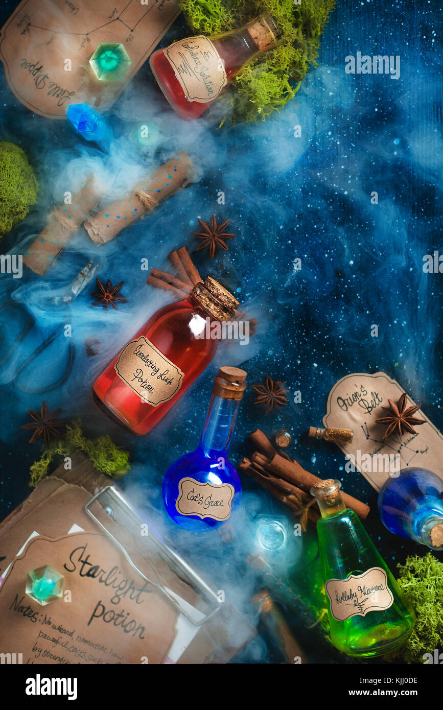 Colorful bottles of magical potions with handwritten labels, steam and oss on a dark wooden background. Fantasy concept with recipes and spells of bea Stock Photo