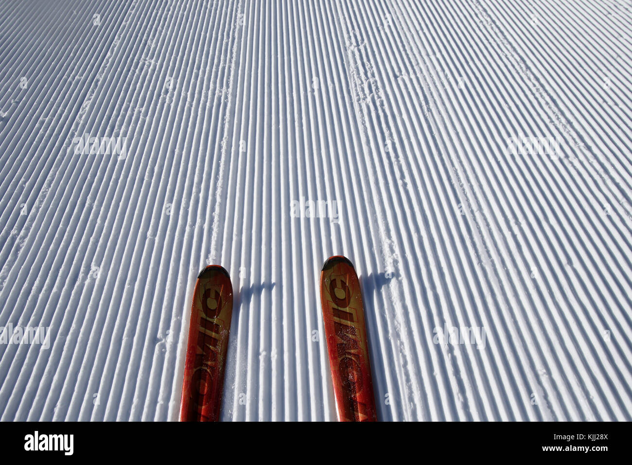 French Alps. Red pair of skis on snow. Groomed Ski slope. France. Stock Photo