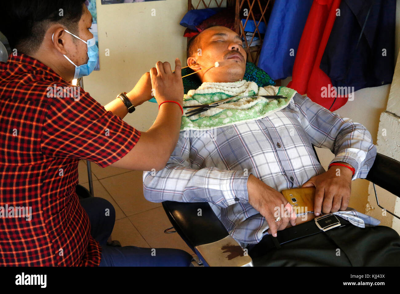 Ear cleaning in a Battambang salon. Cambodia. Stock Photo