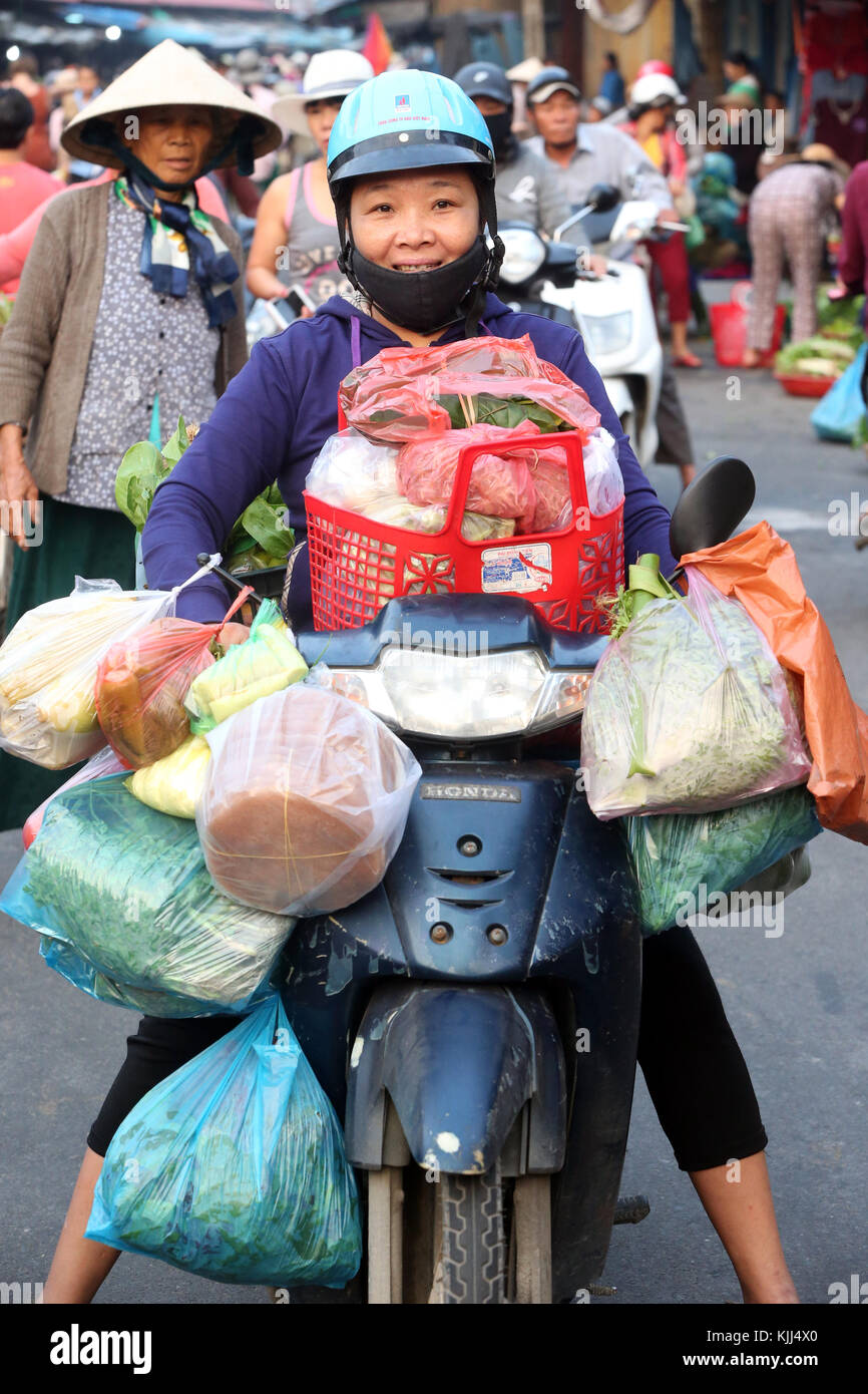 Woman on scooter buying food at market.  Hoi An. Vietnam. Stock Photo