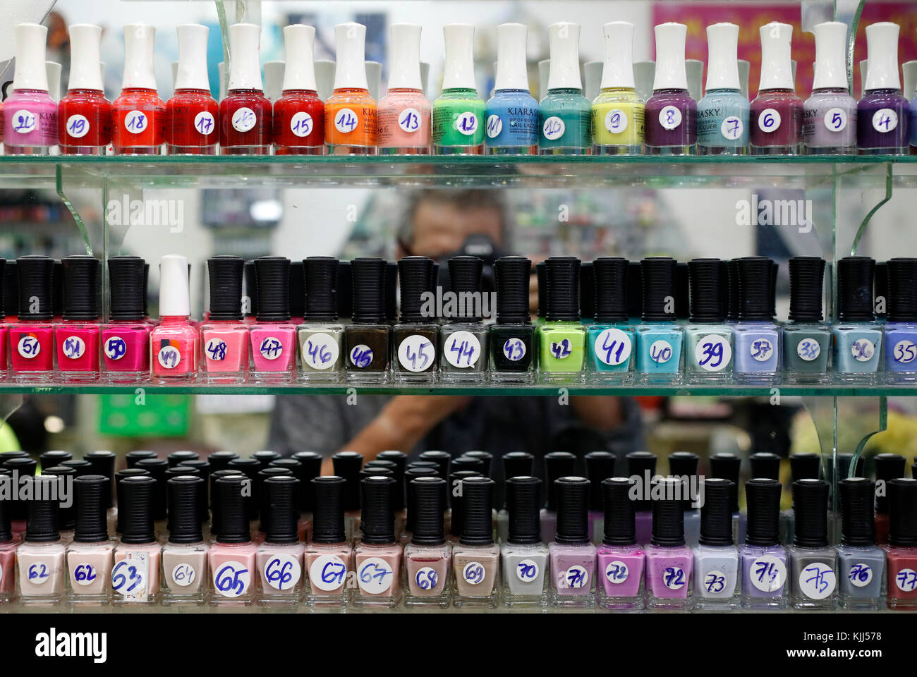 Shelves holding rows of bottles of nail varnish in a nail salon. Ho Chi