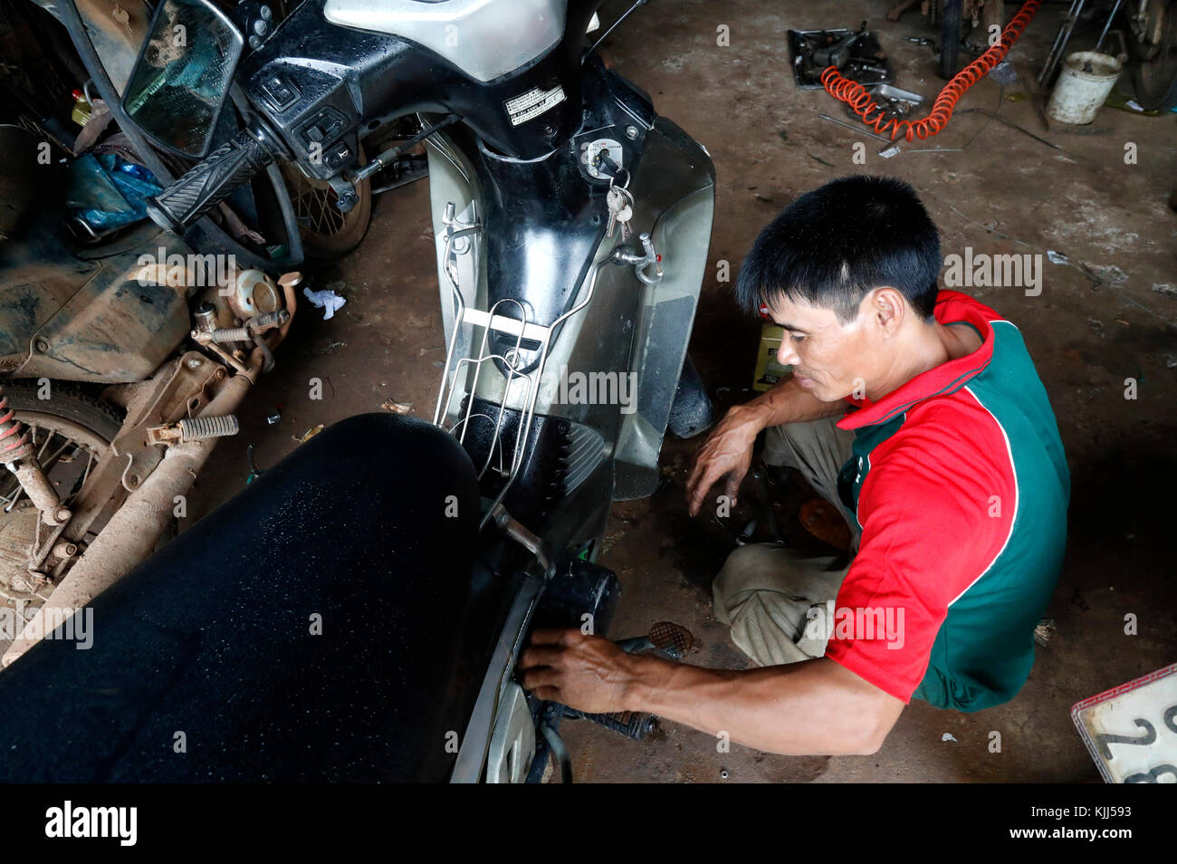 Mechanic repairing motorbike at local garage.  Kon Tum. Vietnam. Stock Photo