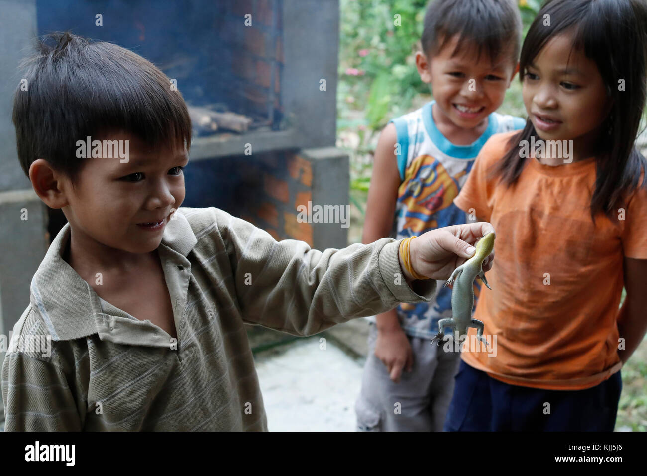 Bahnar (Ba Na) ethnic group. Young boy playing with a lizard.  Kon Tum. Vietnam. Stock Photo