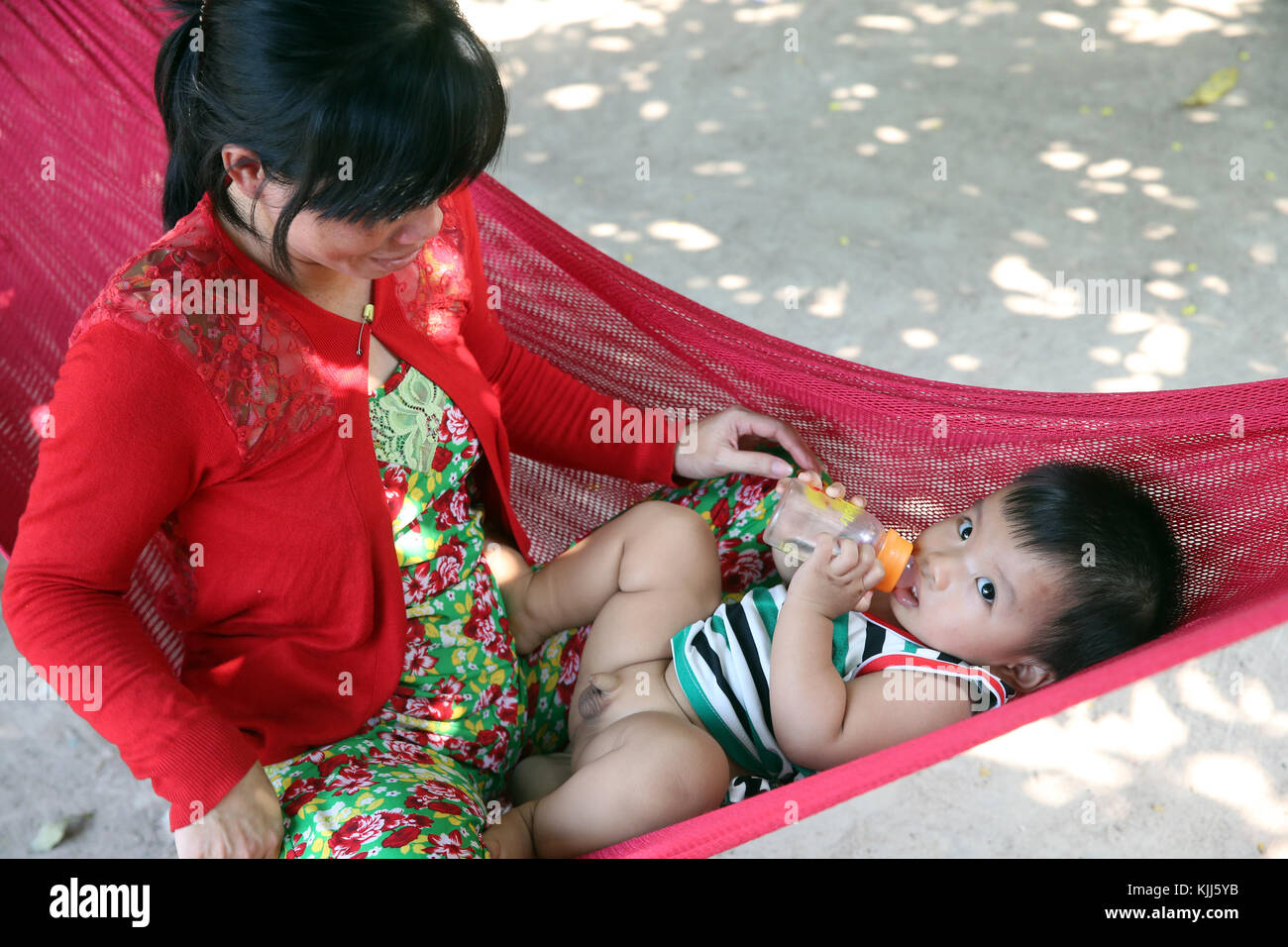 Mother and child relaxing in hammock. Thay Ninh. Vietnam. Stock Photo