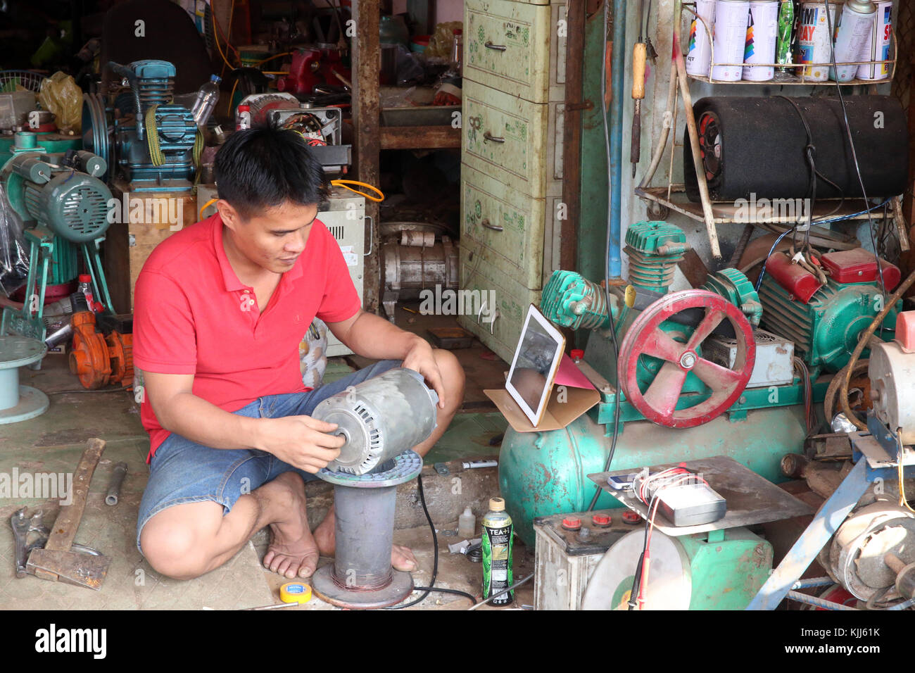 Mechanic working on a compressor in his shop.  Thay Ninh. Vietnam. Stock Photo