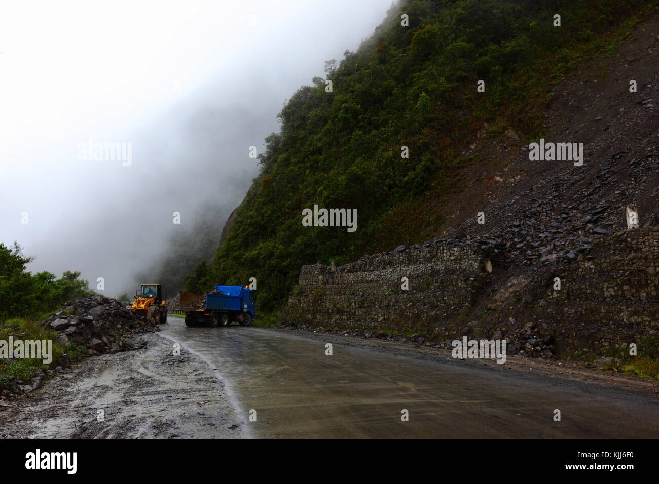 Road workers clear a small landslide from La Paz - Santa Barbara road in rainy season, Yungas region, Bolivia Stock Photo