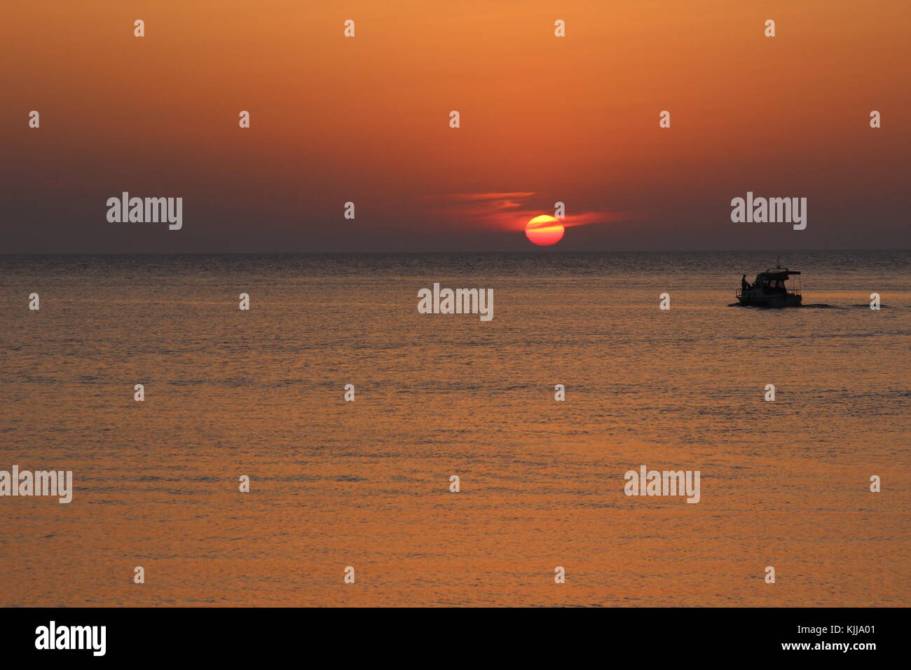 Boat silhouette while Sunset over rock Stock Photo - Alamy