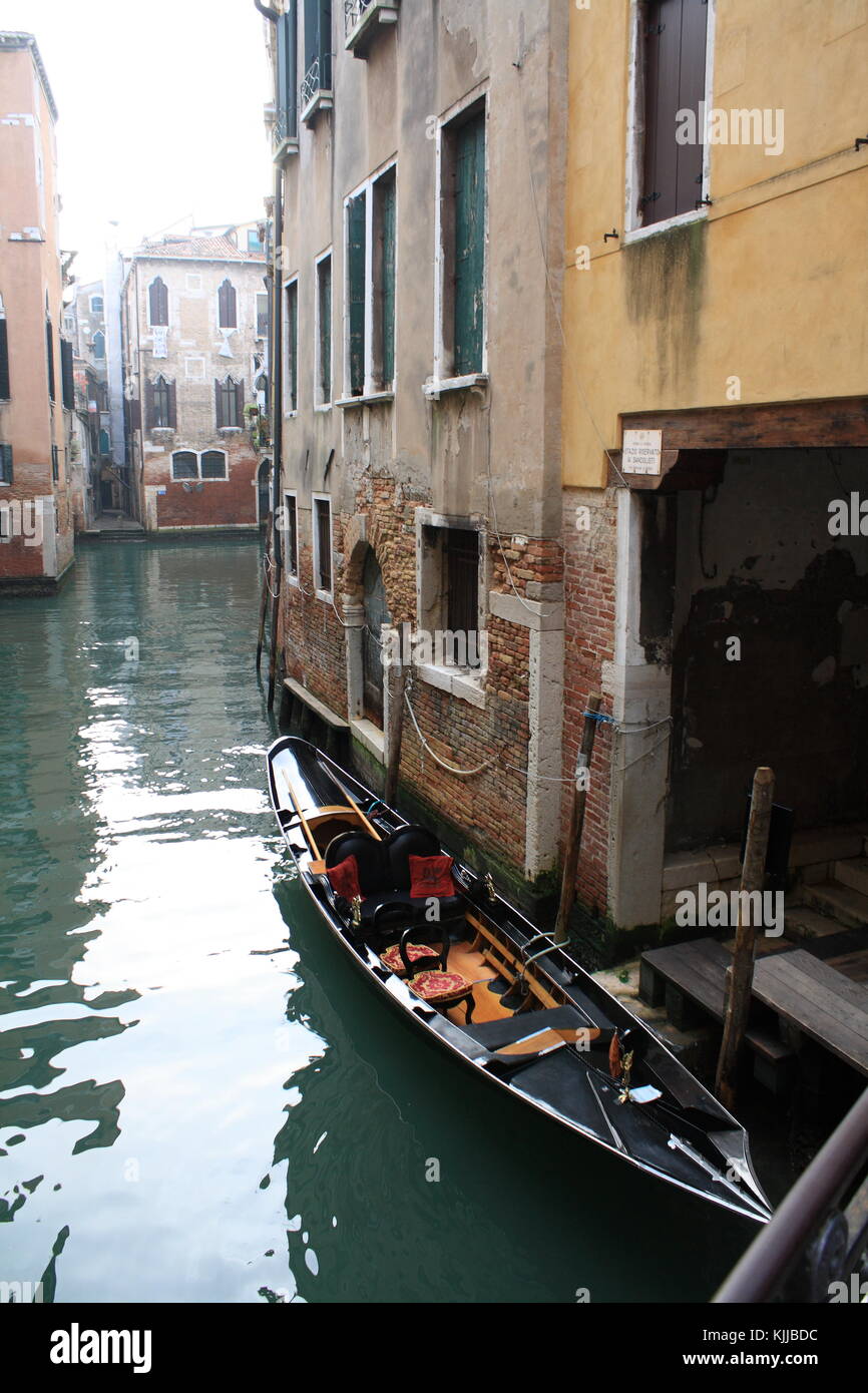 A typical canal in Venice, Italy. A gondola on sea water near the old monument house Stock Photo