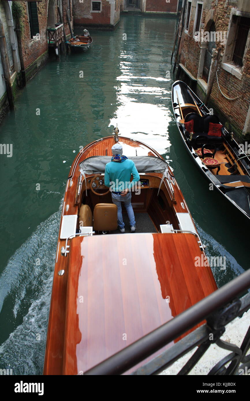 A motor boat taxi passing by in a narrow venice canal in Italy Stock Photo