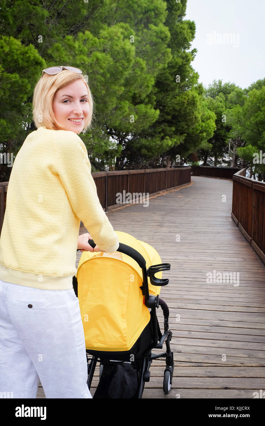 Smiling mother strolling a baby in carriage Stock Photo - Alamy