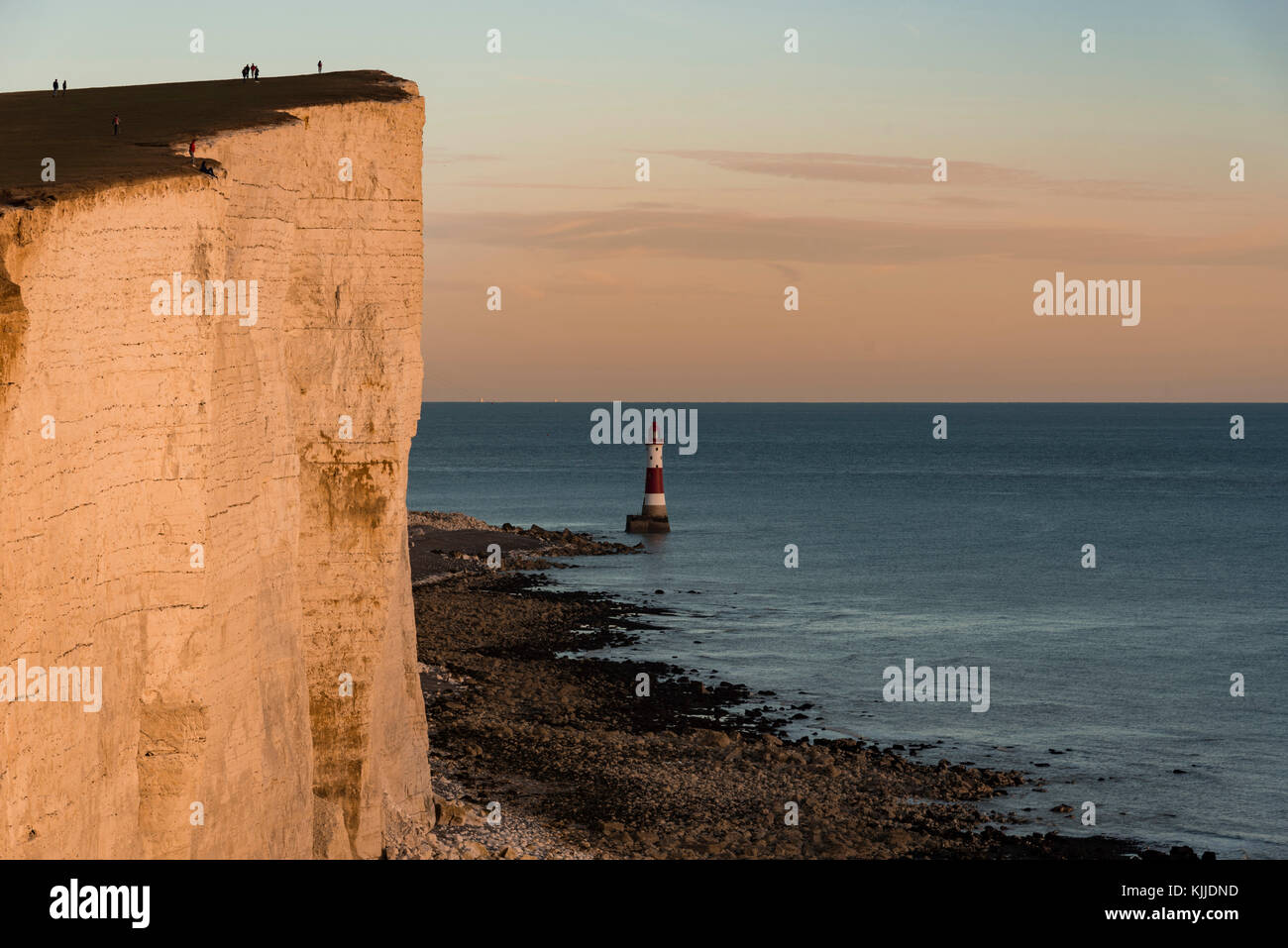 Man dangerously sitting on the cliff edge at Beachy Head at sunset Stock Photo