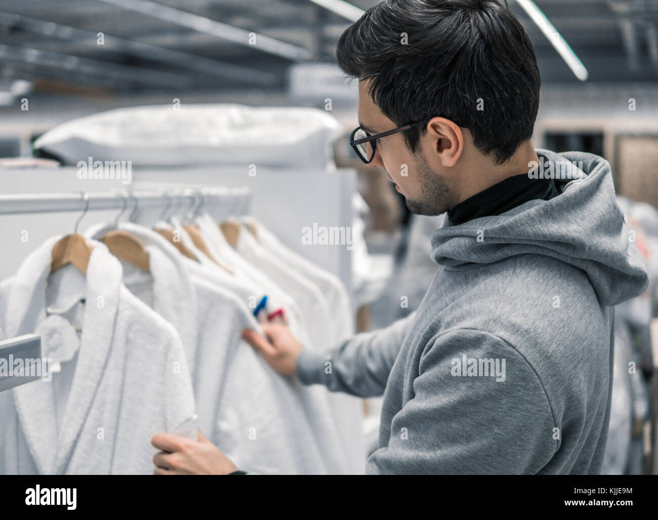 Male Customer inspecting and buying bathrobe in supermarket. White