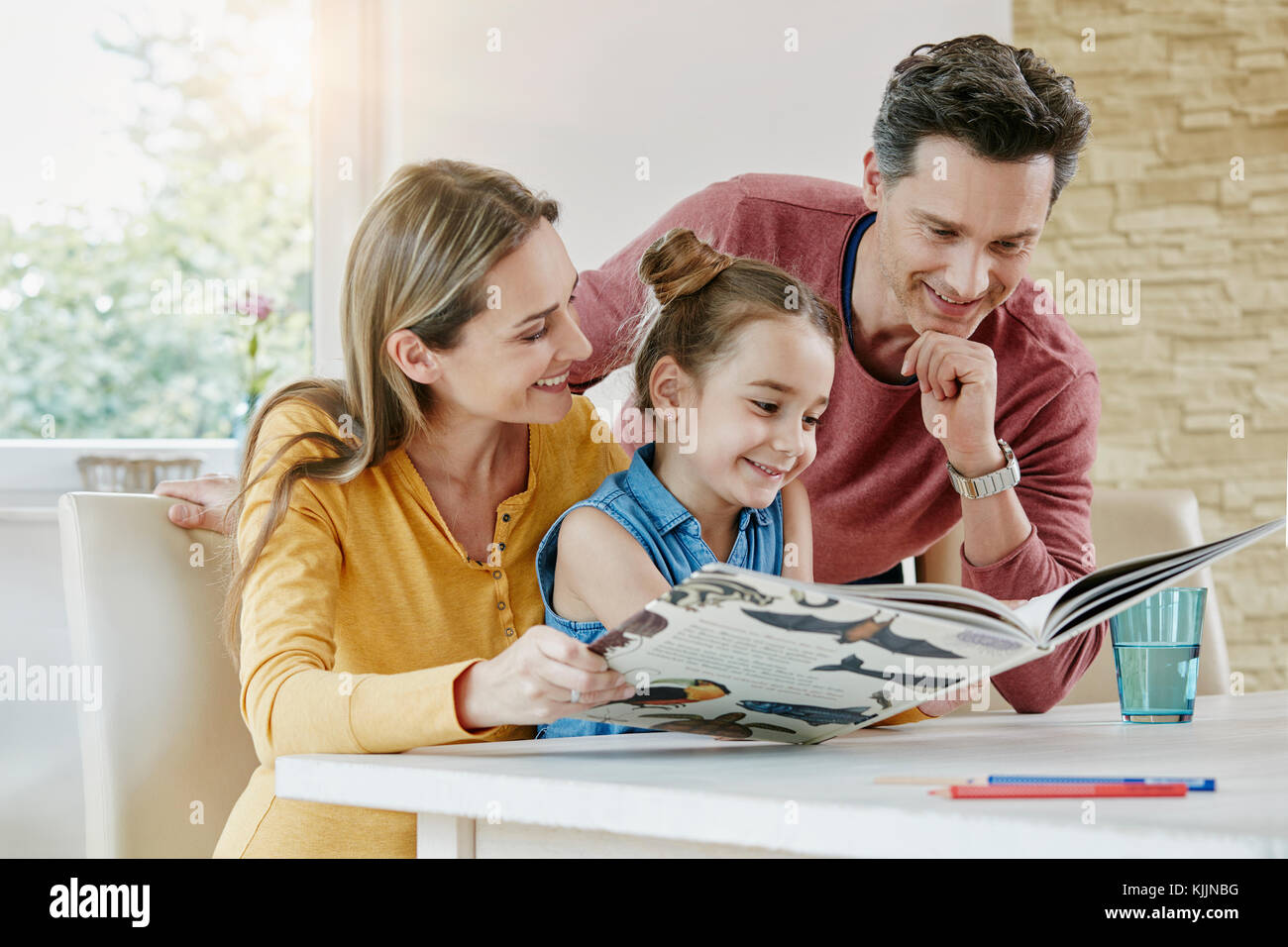Happy family at home looking at picture book Stock Photo