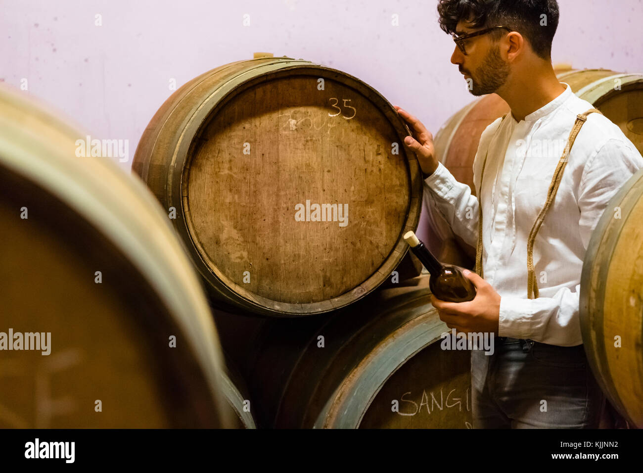 Man looking at wine barrel in wine cellar Stock Photo - Alamy
