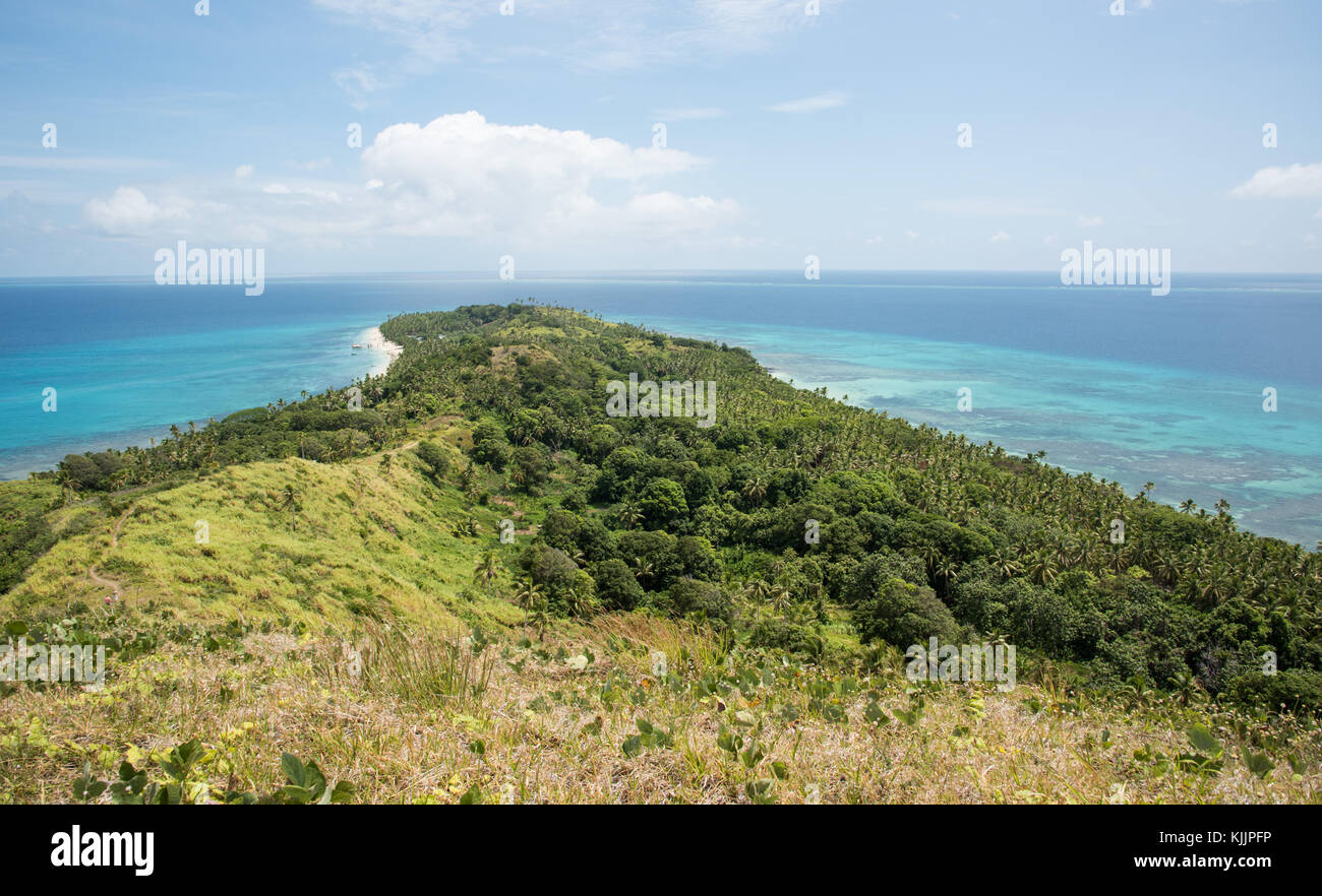 Stunning land and sea views from the lush mountain top under a blue sky with clouds on Dravuni Island, Fiji Stock Photo