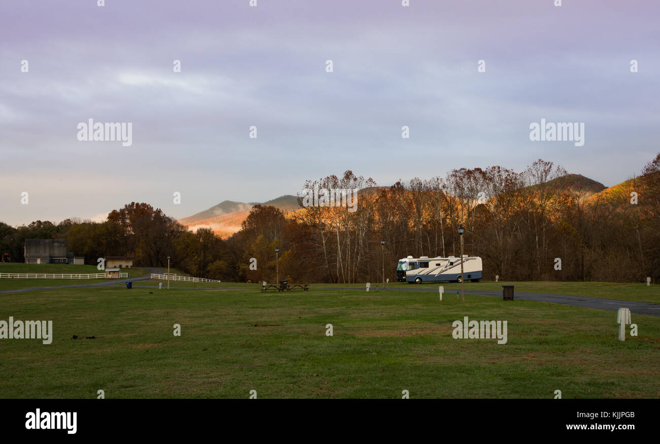 Motorhome parked in a campground in front of mountains, at sunset Stock Photo