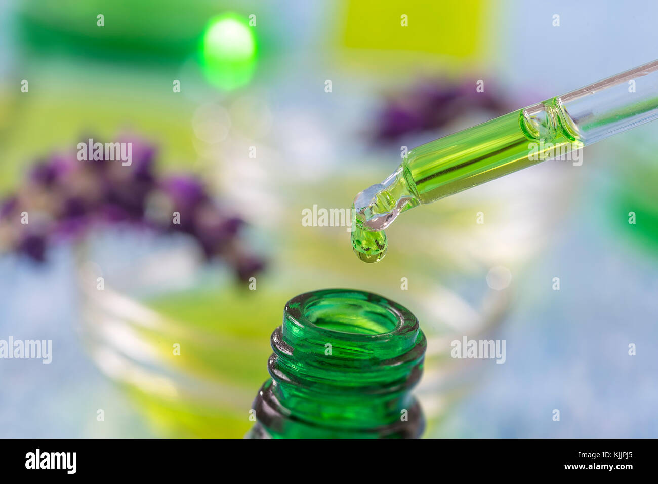 green glass bottles with drops lavender Essential liquid in dropper on wooden background with medicinal flowers Stock Photo