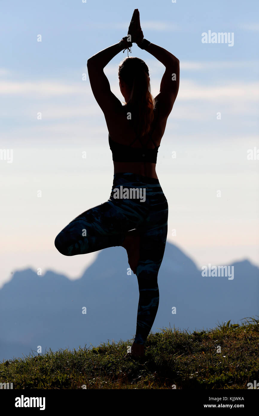 A woman performs a Hatha Yoga pose on a mountain top. French Alps. France. Stock Photo