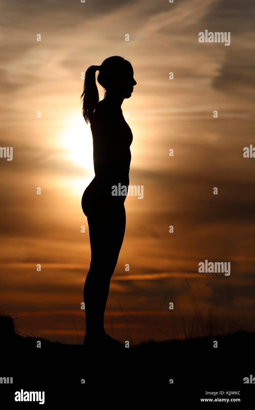 Silhouette of a woman practicing yoga against the light of the evening sun.  French Alps. France. Stock Photo