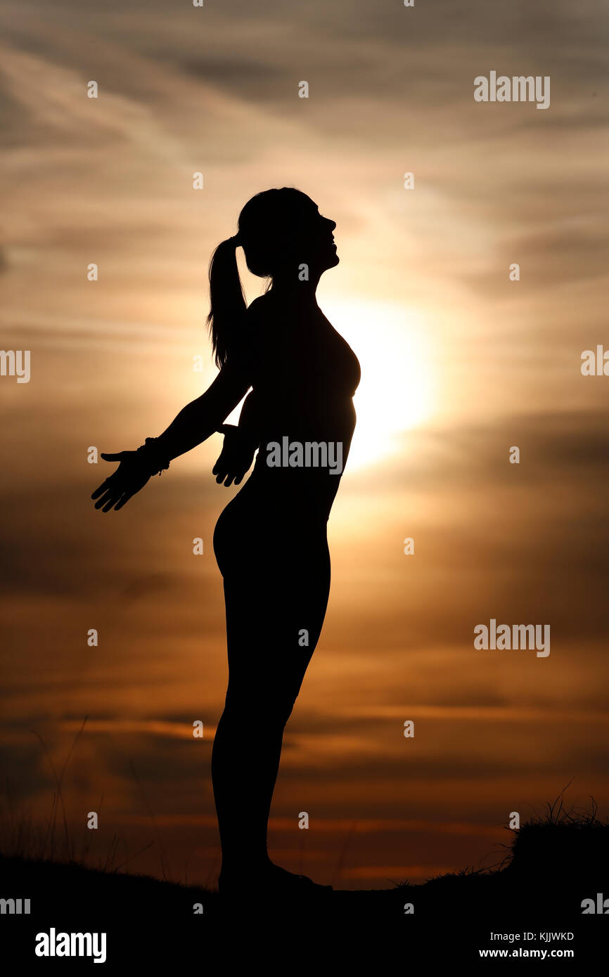 Silhouette of a woman practicing yoga against the light of the evening sun.  French Alps. France. Stock Photo