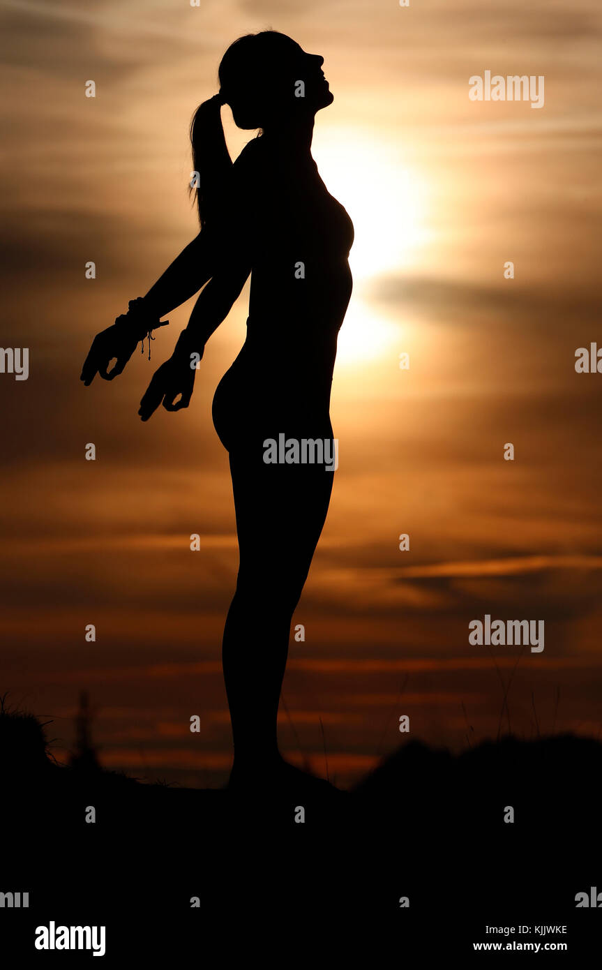 Silhouette of a woman practicing yoga against the light of the evening sun.  French Alps. France. Stock Photo