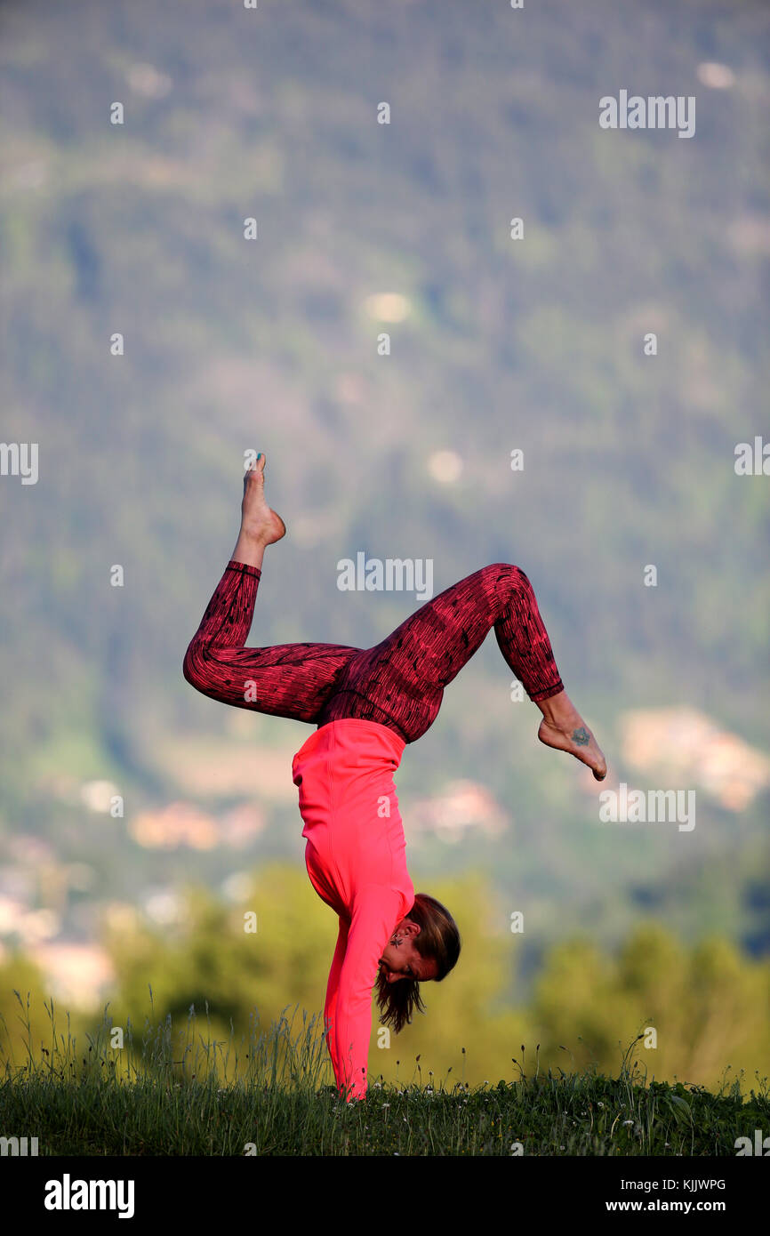 Woman doing yoga and meditation outside. Handstand with Splits. Stock Photo