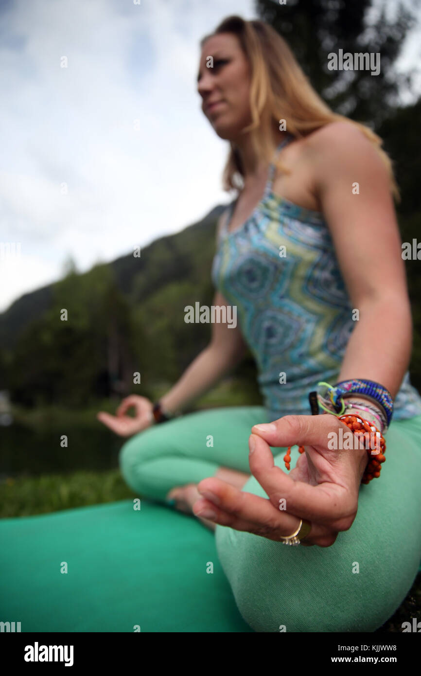 Woman performing yoya outside. Lotus position and mudra posture. Close-up.  France. Stock Photo