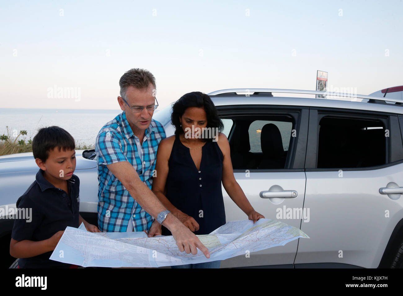 Vacationing family looking at a map. Stock Photo