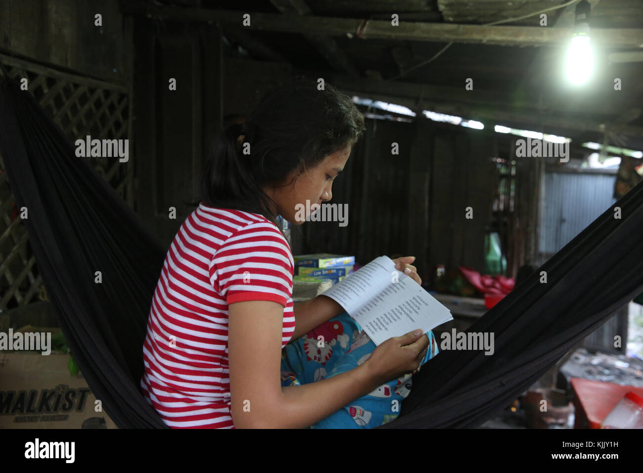 Girl reading in her slum home. Battambang.  Cambodia. Stock Photo