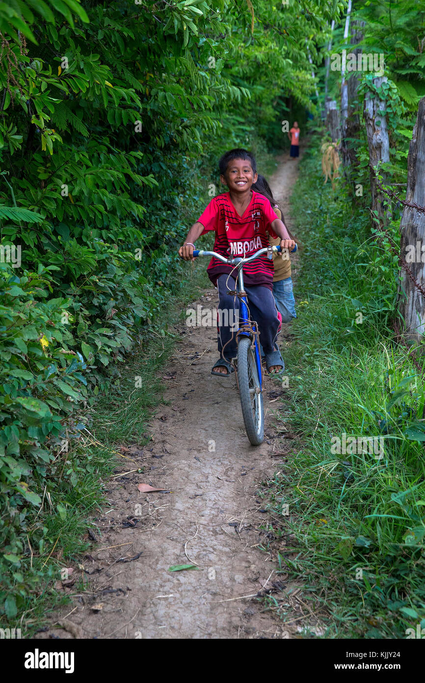 Children riding a bike on a country lane. Battambang.  Cambodia. Stock Photo