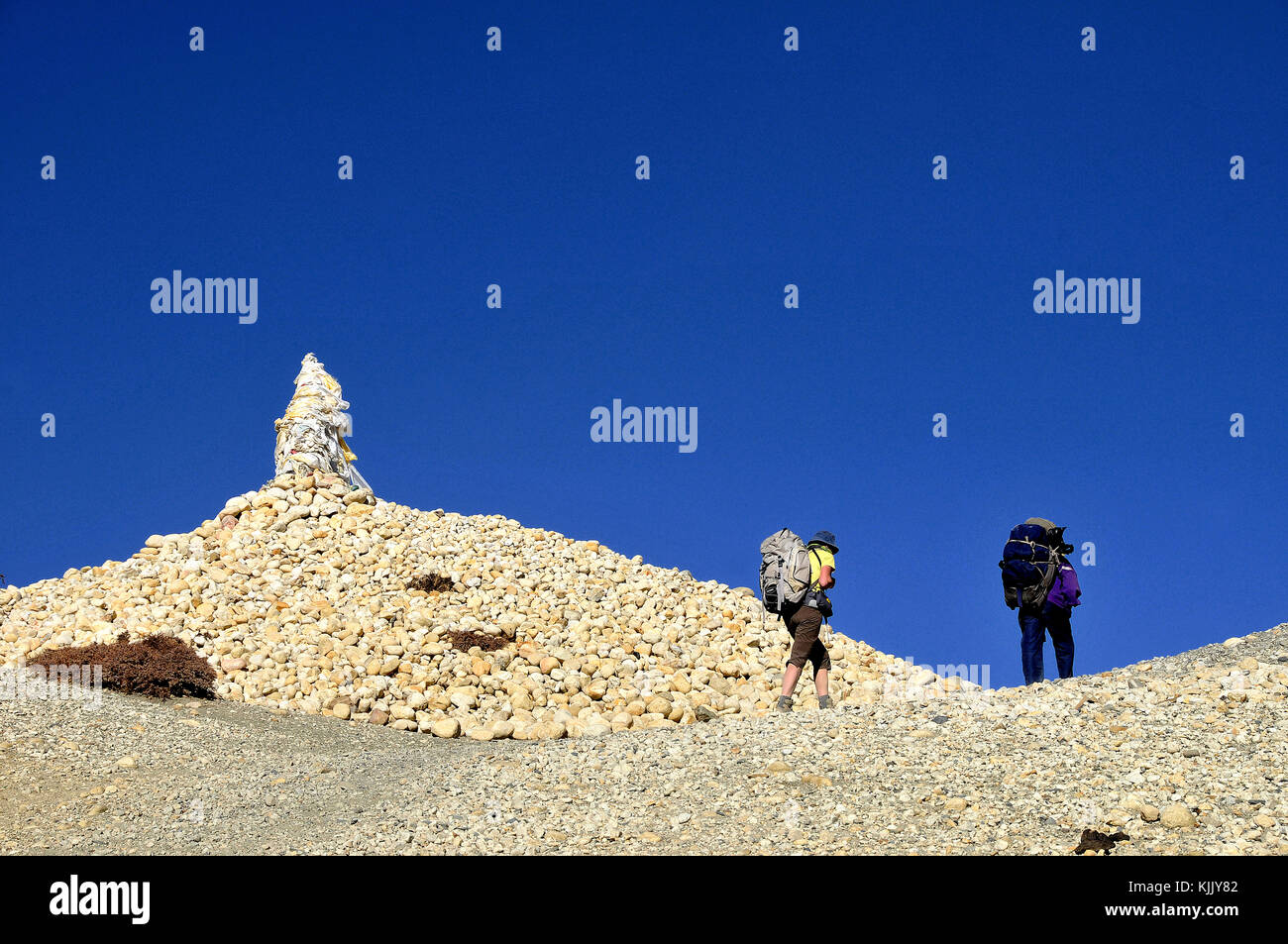 Trekkers walking past a cairn at Ghami pass, Mustang. Nepal. Stock Photo
