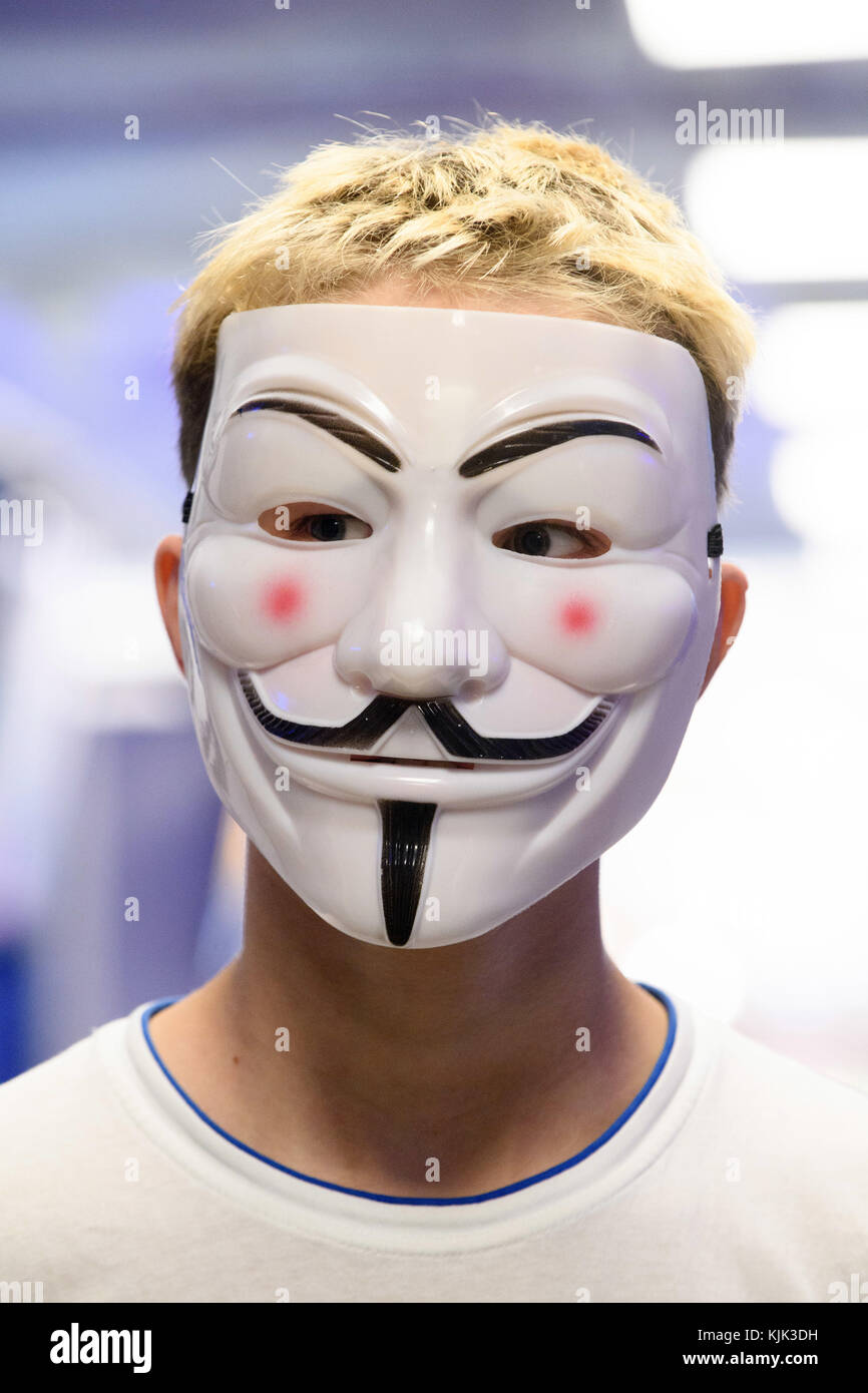 A young man wearing an Anonymous mask. The mask is modeled on English  Catholic officer Guy Fawkes, who was involved in the Gunpowder Plot in the  early 17th century. Many centuries later,